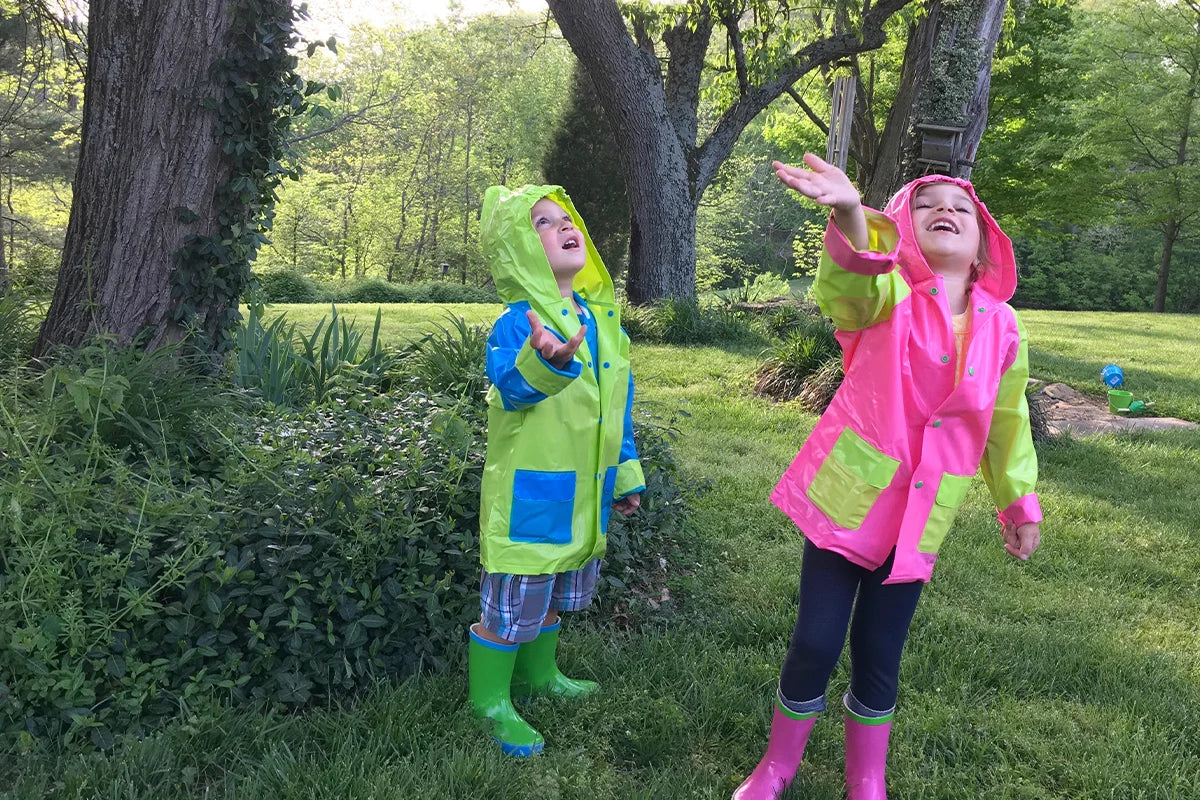A boy and girl having fun outside dancing in the rain and playing with kid size gardening tools