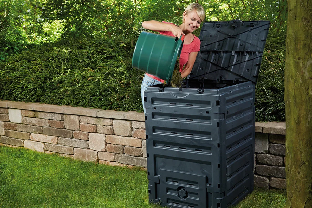 Woman pouring food scraps into a large, lawn compost bin.
