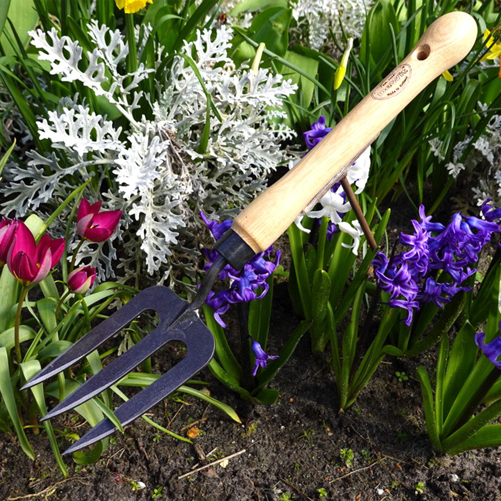 A DeWit Garden Fork displayed among white, purple, and pink flowers.