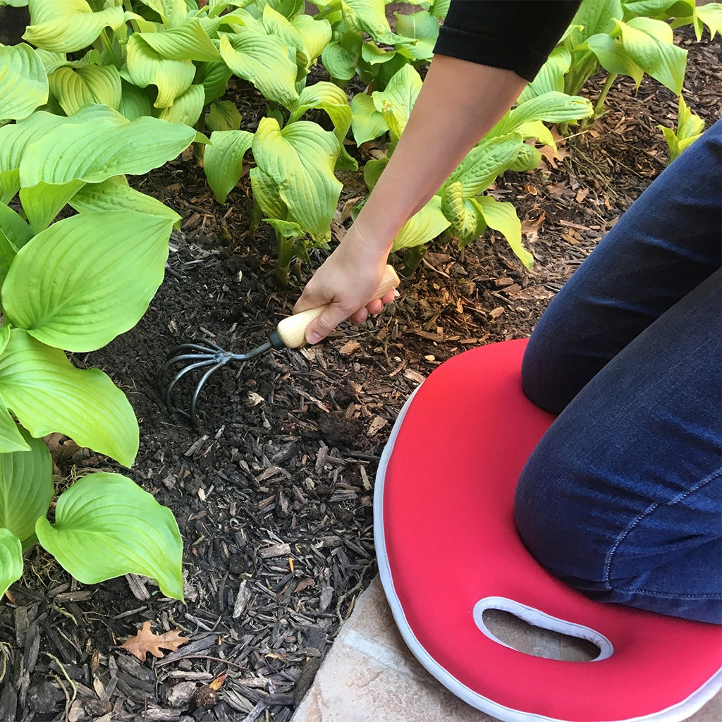 A gardener uses the memory foam kneeling pad on the pavement to complete a weeding job in the garden. 
