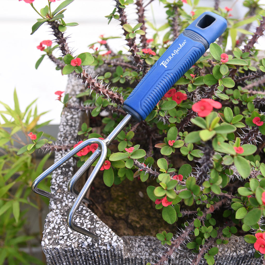 Stainless steel, pro-grade garden fork displayed in front of a planter box.