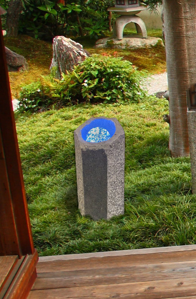 Granite rolling ball stone water feature in garden setting.