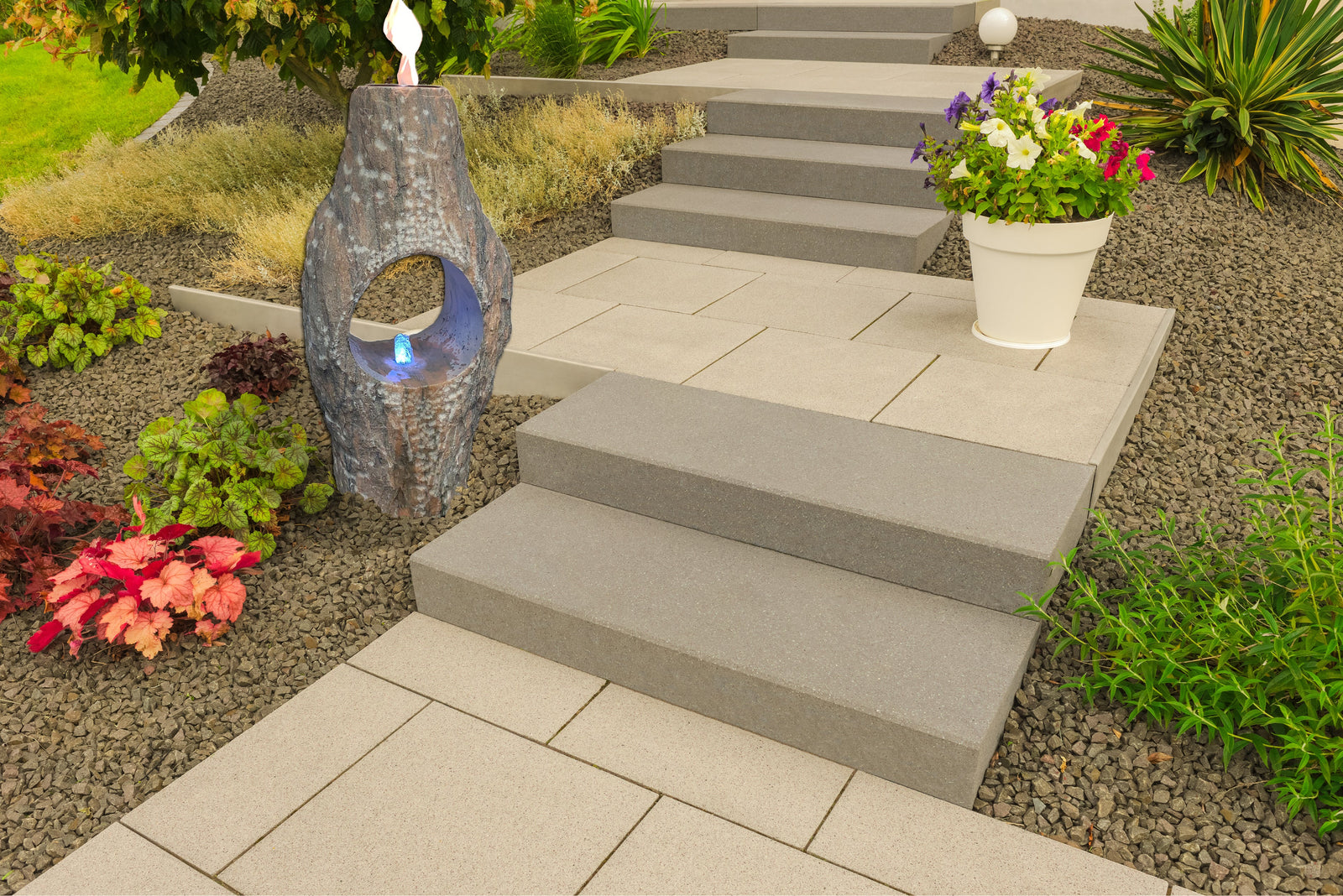 Pink Fire Fountain stone column in a landscaped garden setting.