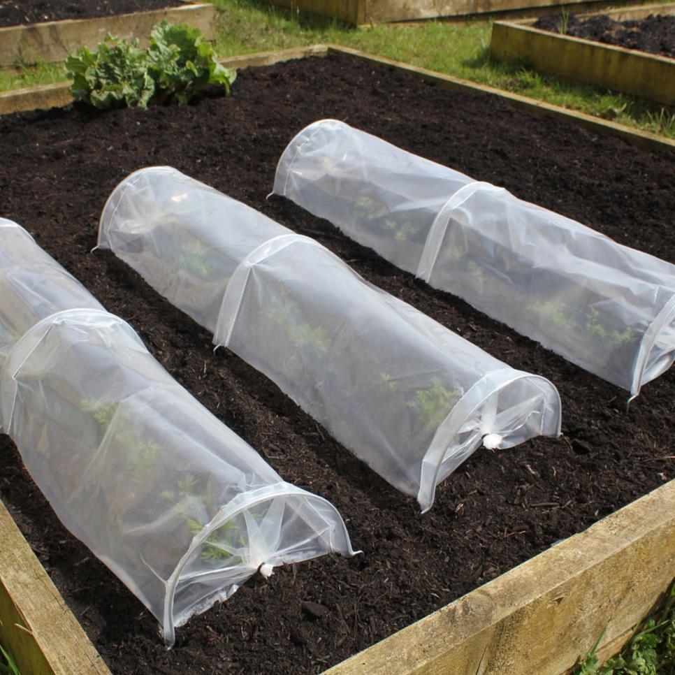 UV-stabilized seedling tunnels protecting plants in a garden bed.